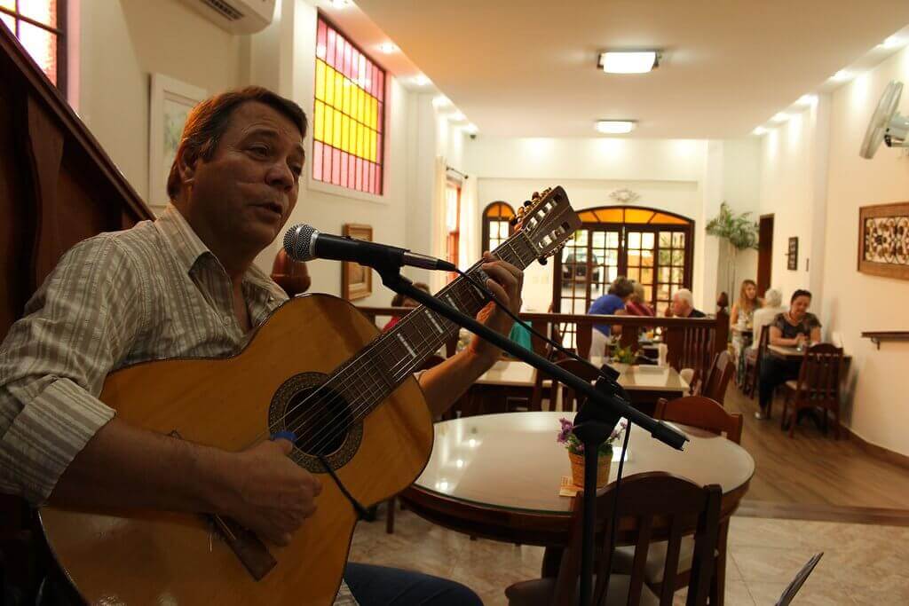 foto de um violeiro cantantando e tocando no café da manhã da Pousada Luar da Serra